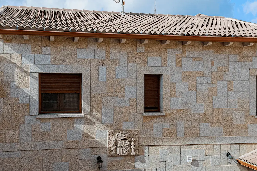 Fachada de granito rubio abujardado con escudo de España tallado