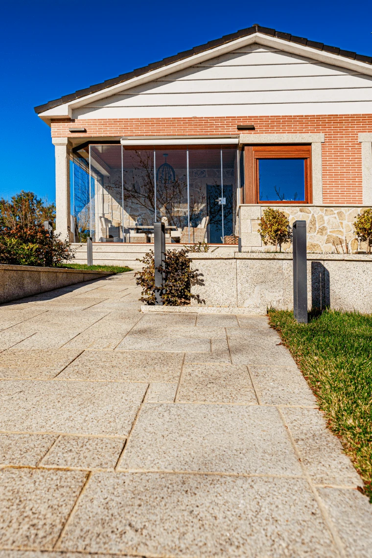 Paseo solado con formato desconcertado en granito rubio abujardado.